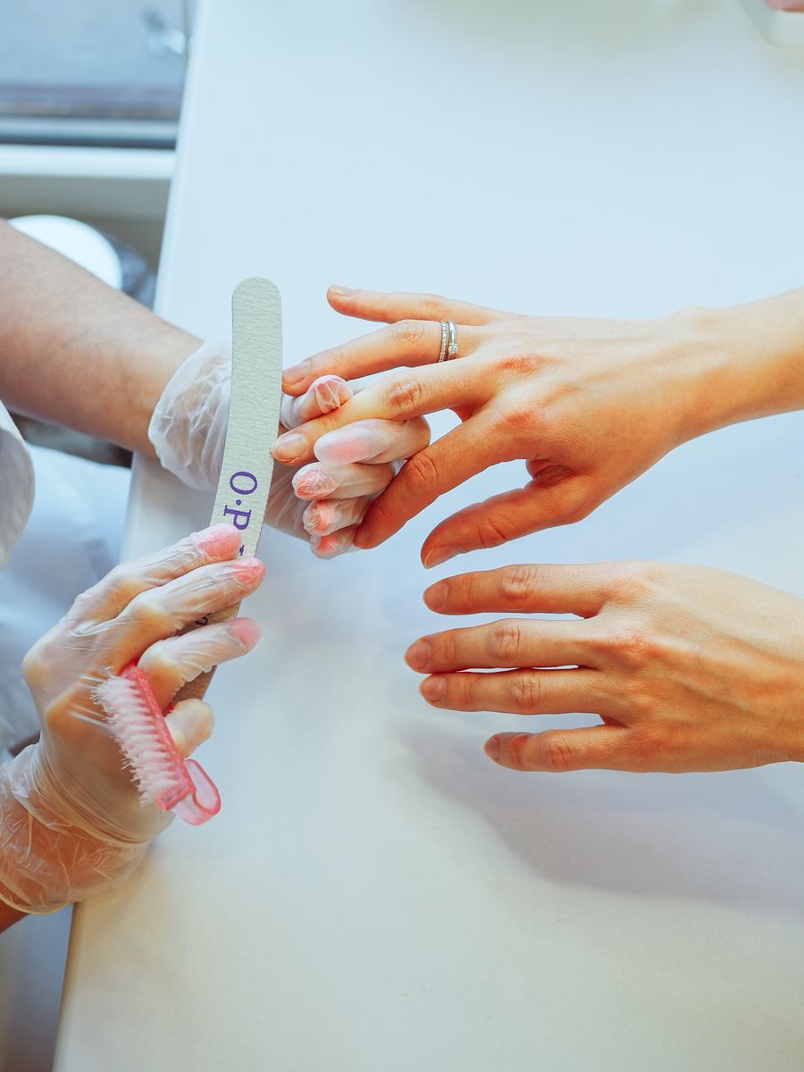 Manicurist filing a client's nails